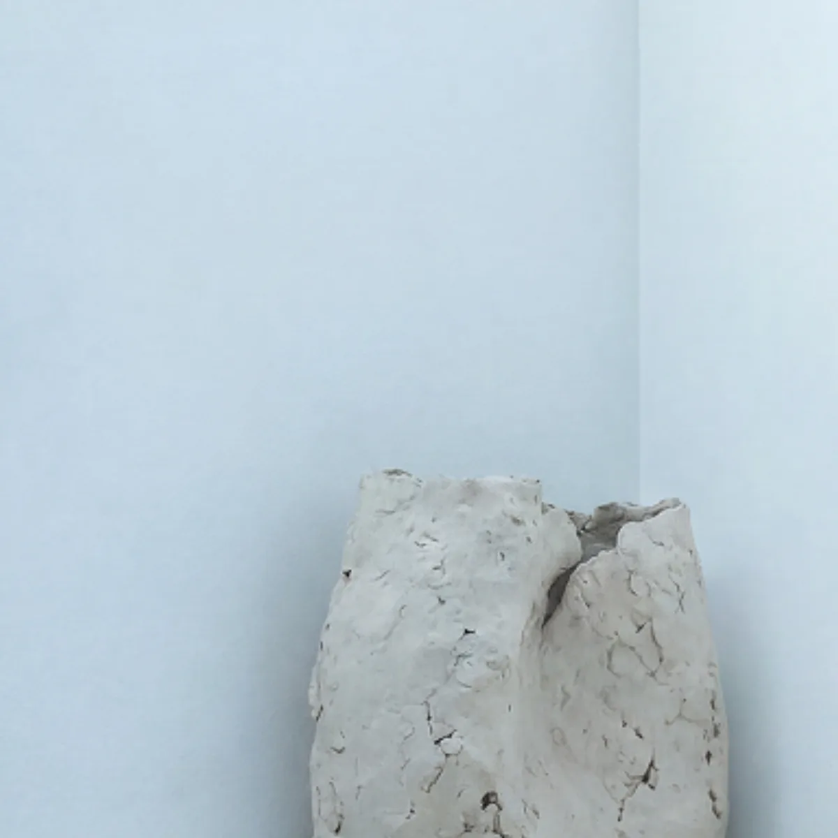 Rough stone block leaning against a pale blue wall